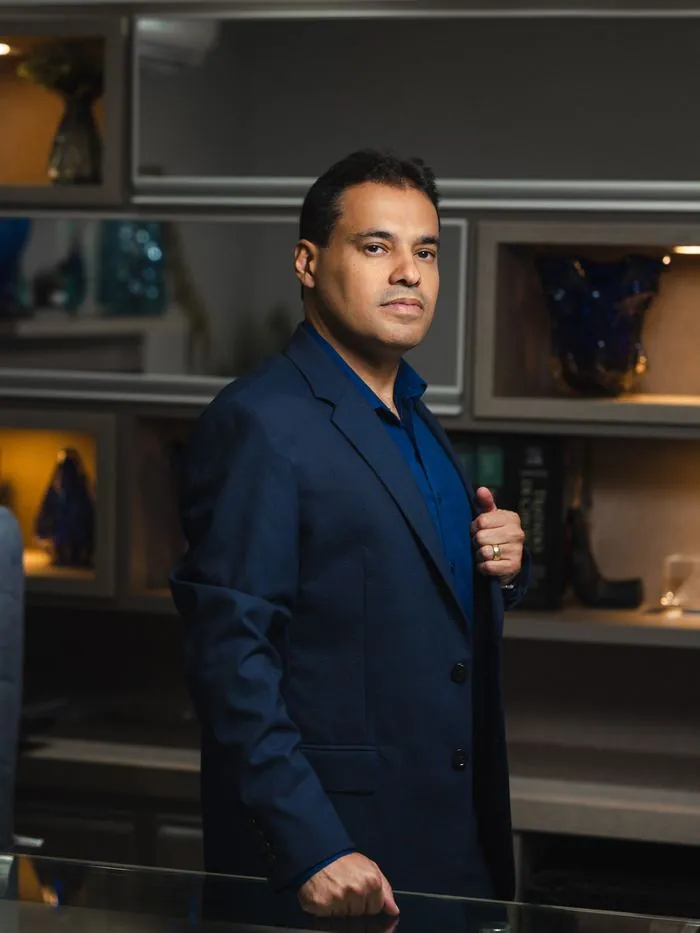 Dr. Vitor Duarte em pé no consultório, com estante decorada ao fundo